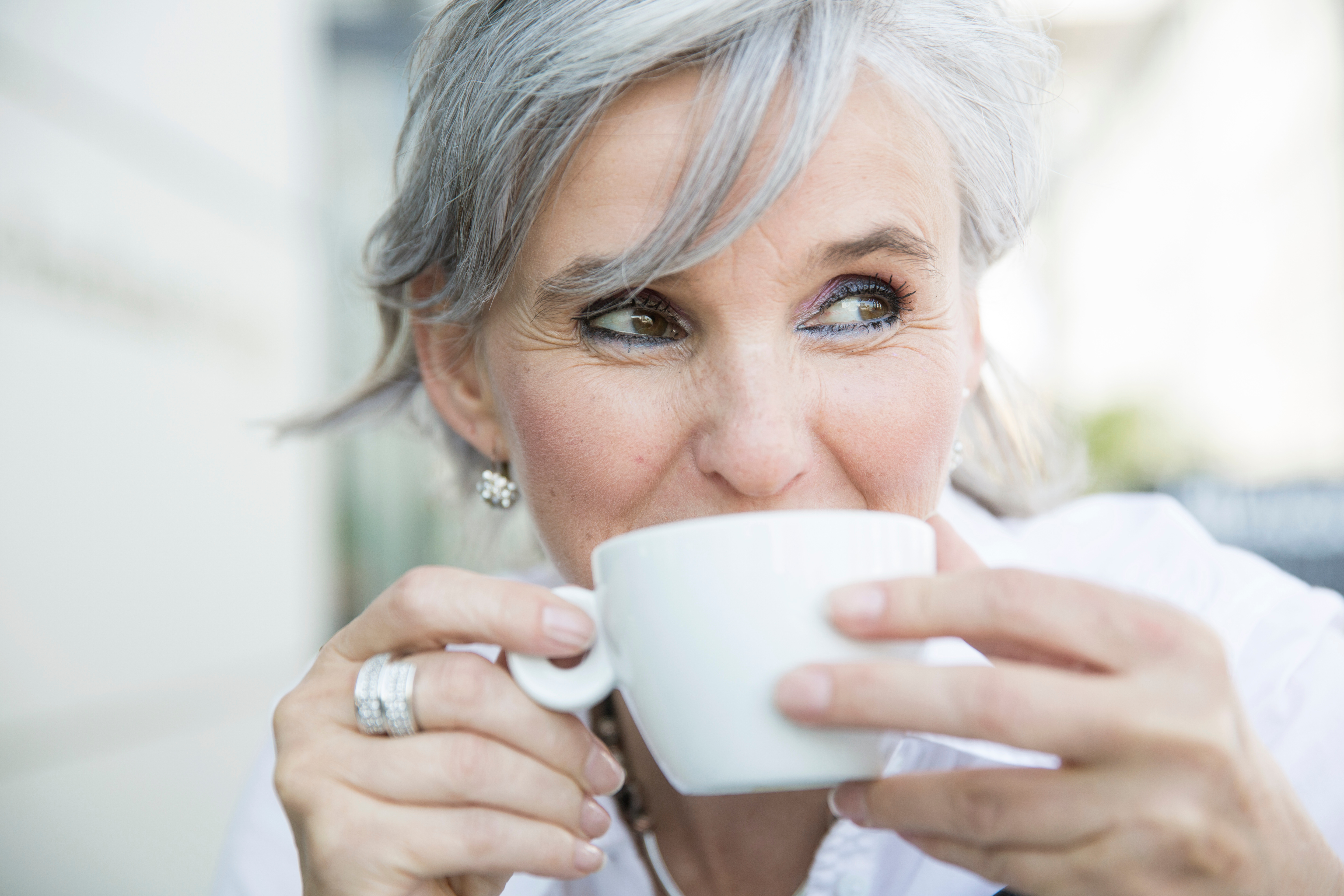 Porträt einer entspannten Frau in der Menopause beim Kaffeegenuss – natürlich, stark und lebensfroh.