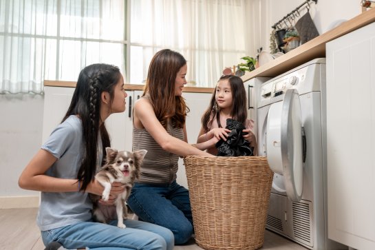Eine Mutter mit ihren beiden Kindern vor der Waschmaschine