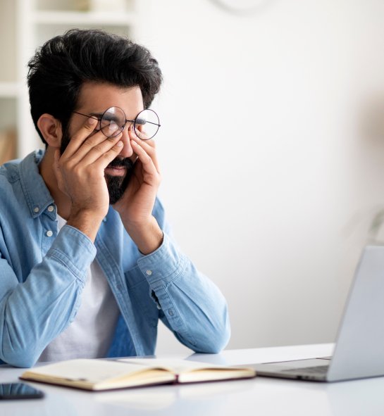 Un homme se frotte les yeux d'un air fatigué devant l'écran