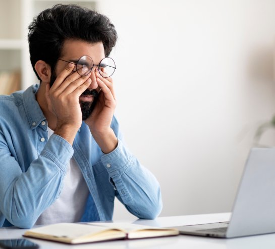 Ein müder Mann vor dem Computer reibt sich die Augen