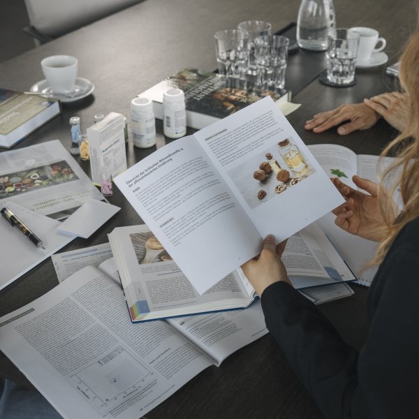 Une femme étudie avec attention des articles universitaires et scientifiques sur les micronutriments