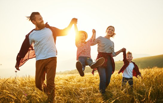 Familie im Sonnenuntergang glücklich spielend auf einer Wiese