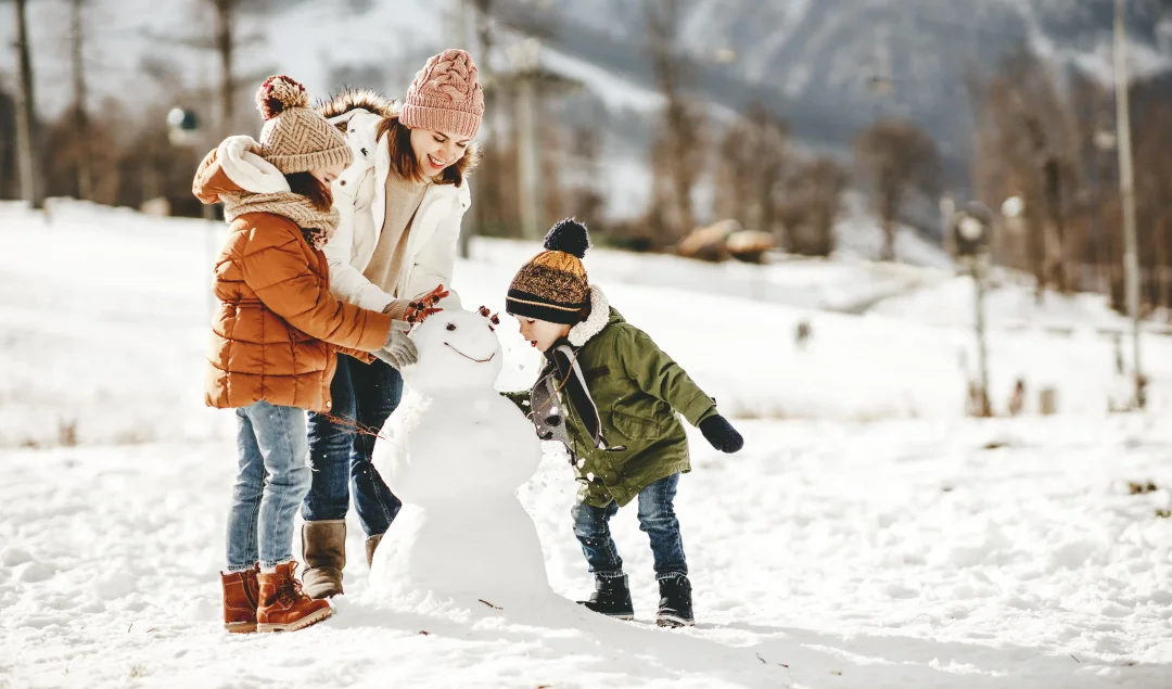 Schneemannbau einer Frau mit ihren zwei Kindern