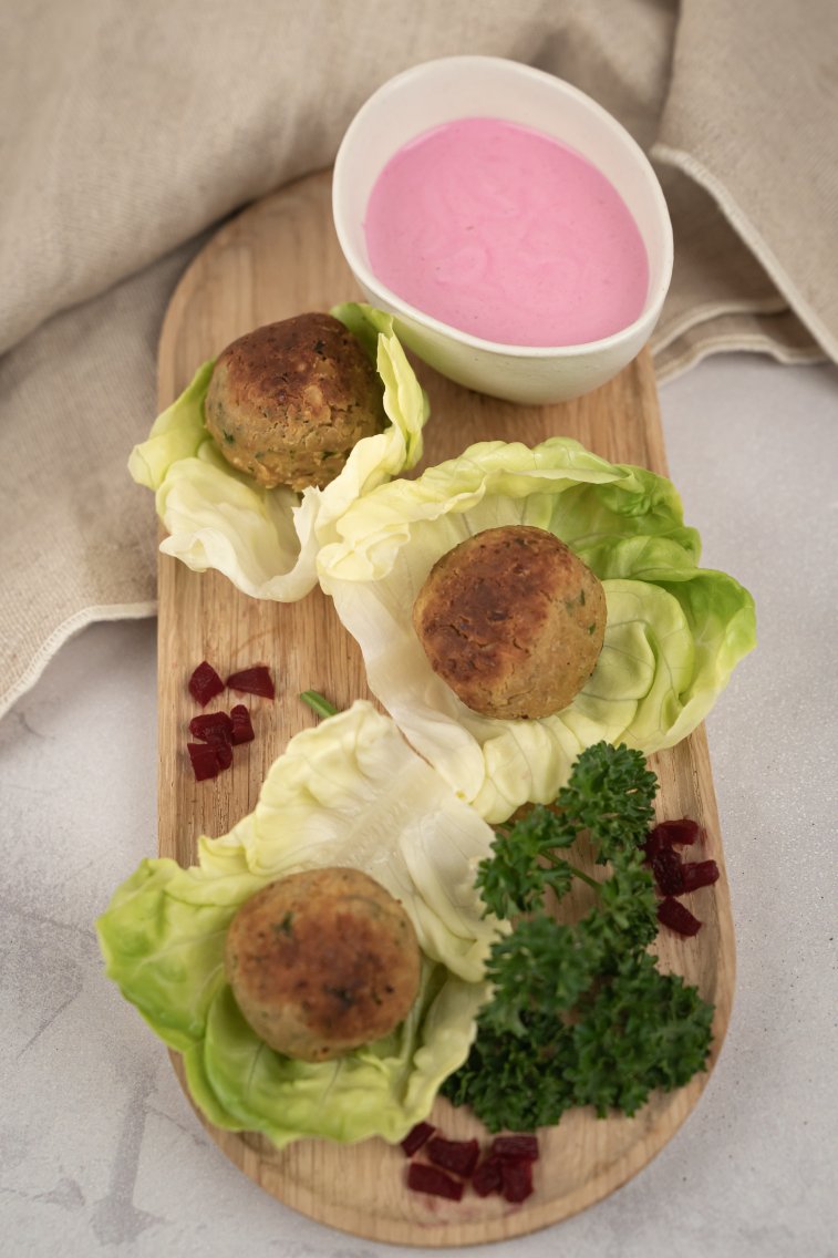 Falafel-Bällchen auf Salatblättern, daneben etwas Petersilie, rote Bete und ein Dip.