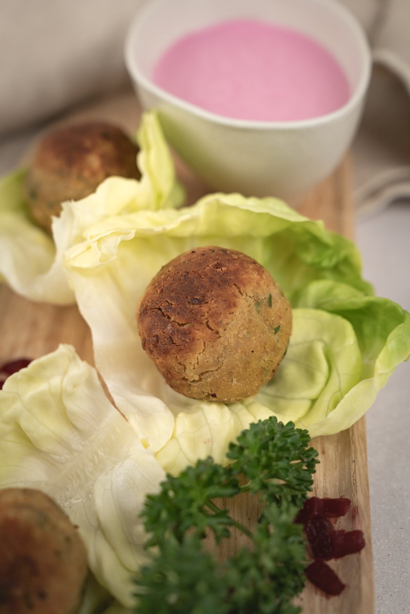 Falafel-Bällchen auf Salatblättern, daneben etwas Petersilie, rote Bete und ein Dip.