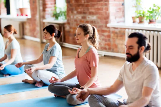 Gruppe Menschen beim Yoga in hellem freundlichen Raum